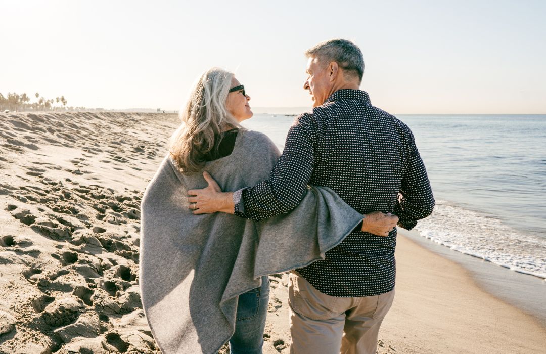 Couple senior marchant sur la plage symbole du vieillissement en bonne santé et de la vitalité après 50 ans