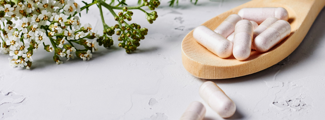 Gélules de complément alimentaire sur une cuillère en bois, à conserver à l’abri de la chaleur