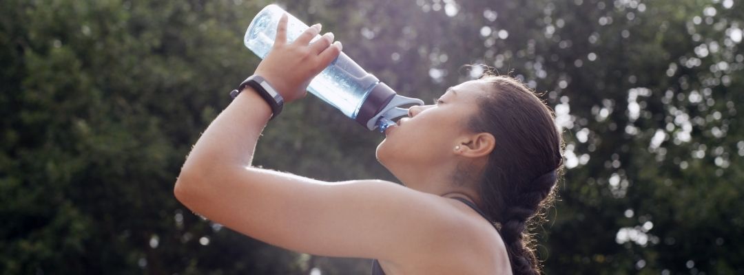 Personne buvant de l’eau pendant un effort en extérieur par forte chaleur
