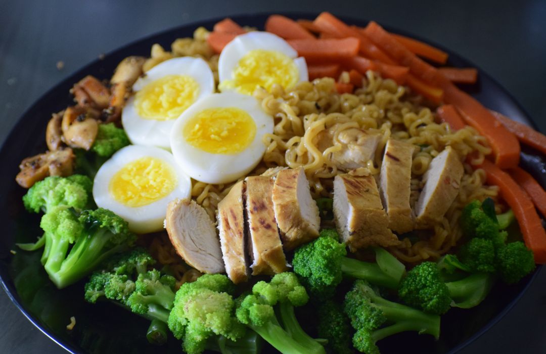 Alimentation équilibrée et performance durable Assiette équilibrée avec œufs, poulet et légumes, illustrant le rôle de l’alimentation dans l’énergie, la récupération et la performance durable